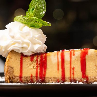 A slice of cheesecake topped with whipped cream and mint.