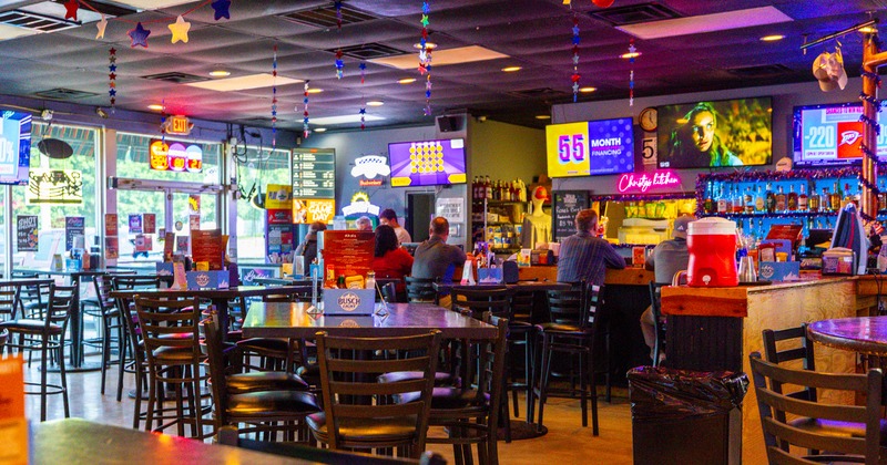 Interior, bar tables and chairs, TV screens on wall