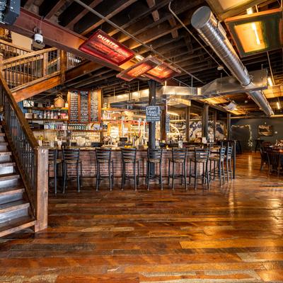 Large space, bar with bar stools, and tables and chairs along the wall