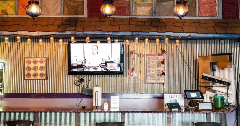 Bar table for dinner with high chairs next to the wall with a TV above