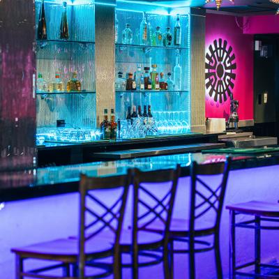 Colorful bar with illuminated shelves and stools.