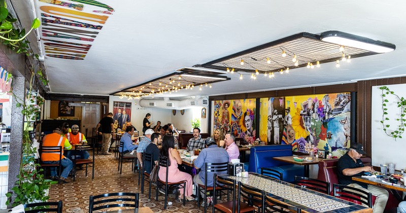 Cozy interior of Mexican restaurant, dining area full of guests enjoying their food