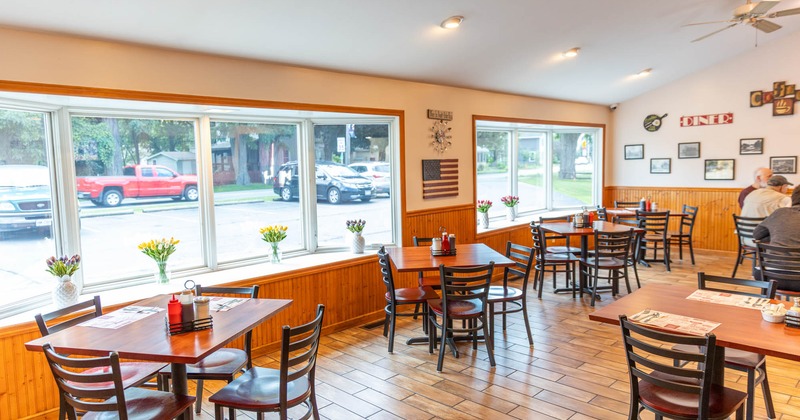 Interior, wooden table top tables for four, large windows, tile flooring, decorative vases