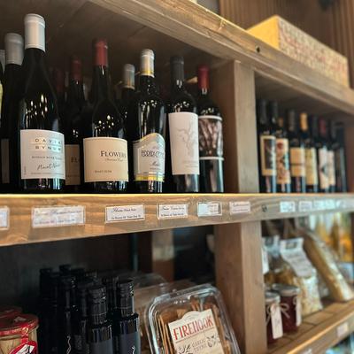 Wine bottles displayed on wooden shelves in a shop.