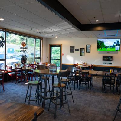Bar area, tables, stools, bar, tv screens.