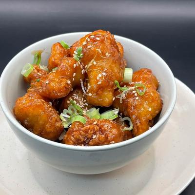 Orange chicken with sesame seeds and scallions.
