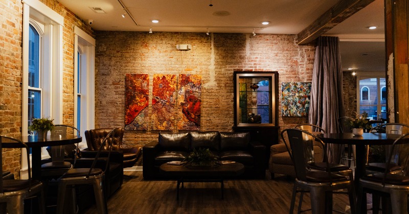 Interior, dining and lounge area, tables with chairs, sofa, various abstract paintings