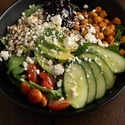Healthy bowl with avocado, grape tomatoes, chick peas, cucumber, and goat cheese.