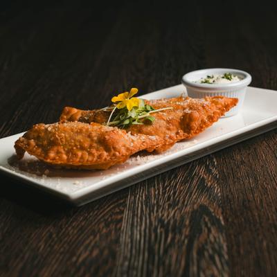 Trio Empanada accompanied by a side of white sauce.