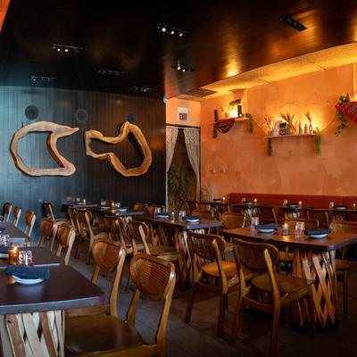 Restaurant interior with wooden tables, wicker chairs, and a warm, earthy color scheme.
