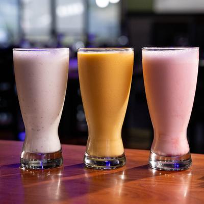 Assorted colorful lassi drinks on a counter.