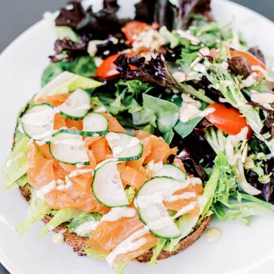Avocado toast with smoked salmon, cucumbers, aioli, and mixed spring salad.