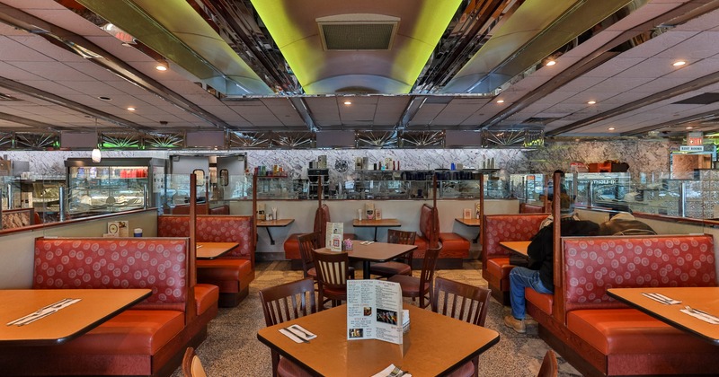 Interior of a retro style diner with red cushioned booths, wooden tables