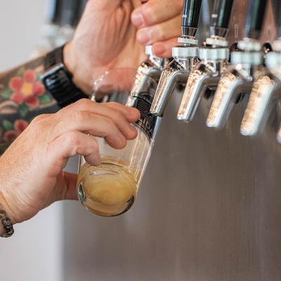 Hands pouring a beer from the dispensary.