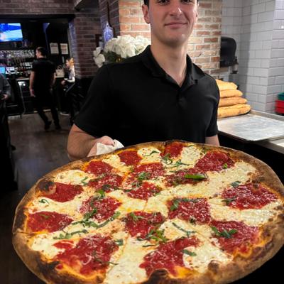 A staff member holding the old world margarita style pizza.