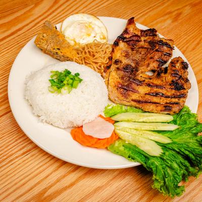 Grilled pork chop with rice, slices of cucumber, lettuce, noodles, and a fried egg.