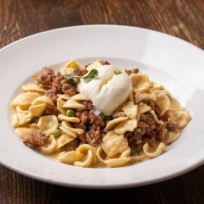Pasta with sausage topped with burrata and herbs.