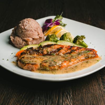 Grilled salmon served with a light pan sauce, scoop of mashed beans and sautéed vegetables.