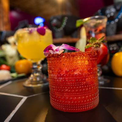 Strawberry mezcal margarita with other cocktails in the background.