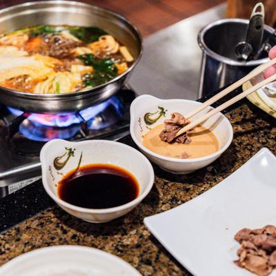 Hot Pot on a gas stove and dipping sauces on the side.
