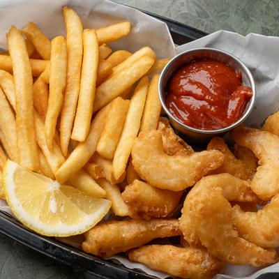 Fried shrimp served with French fries, dipping sauce and a lemon wedge.