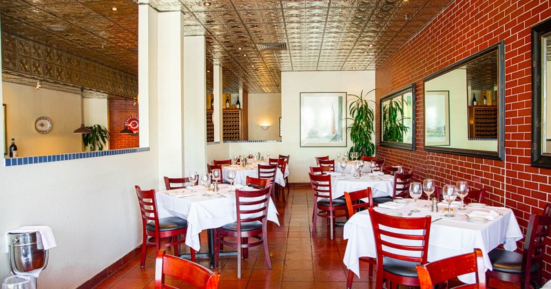 Interior, dining area, tables with chairs, ready for guests, red brick wall, large mirrors