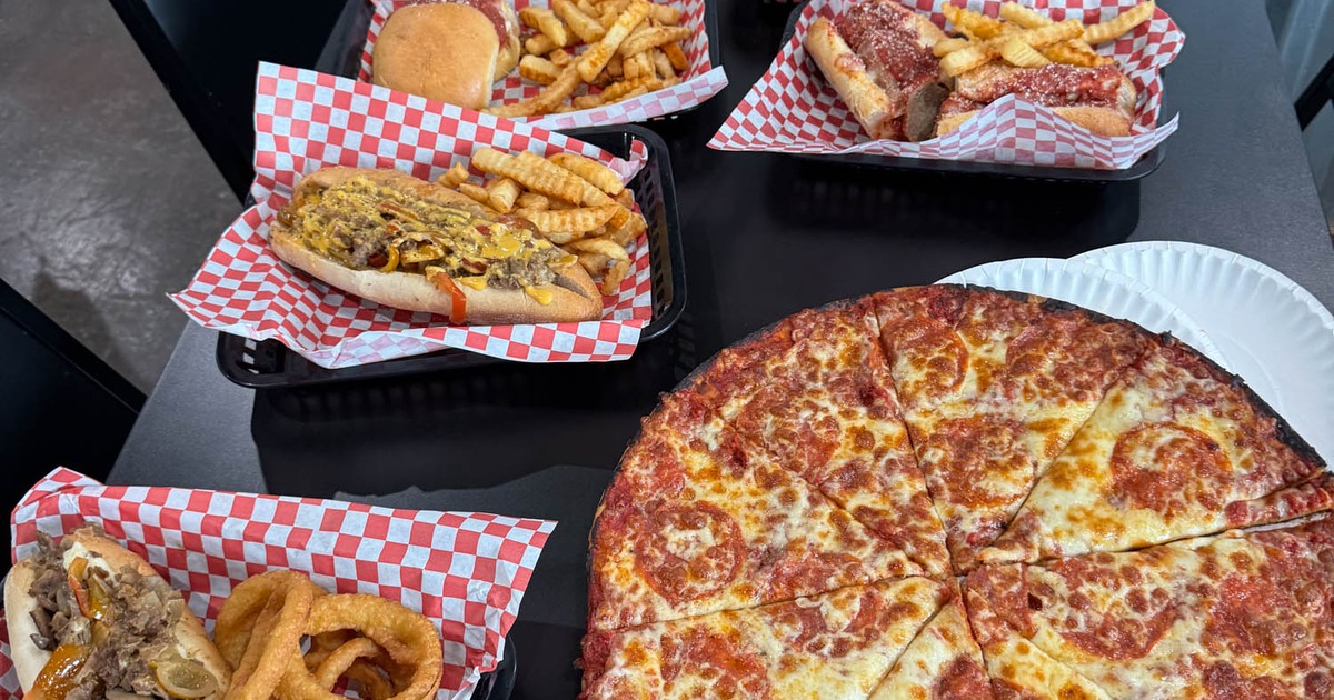 A large pepperoni pizza served with various sandwiches
