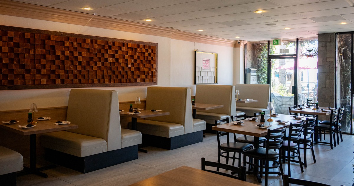 Interior of a modern restaurant featuring beige booths, wooden tables