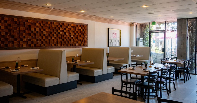 Interior of a modern restaurant featuring beige booths, wooden tables