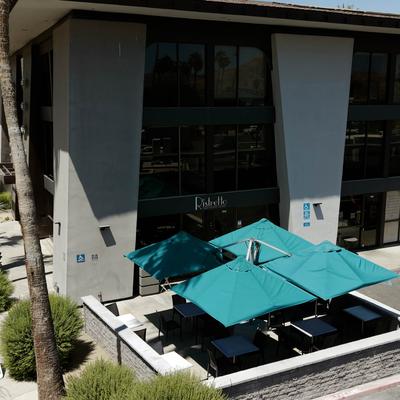 Exterior of a building with blue patio umbrellas.