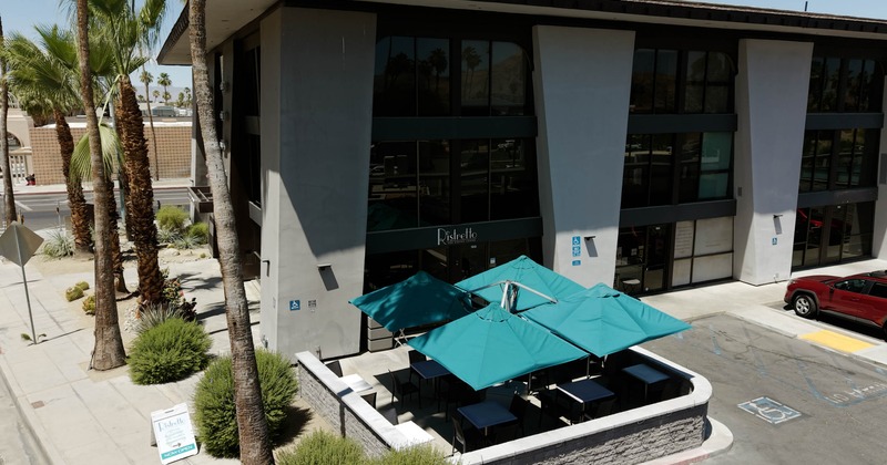 Outdoor patio seating featuring four large teal umbrellas