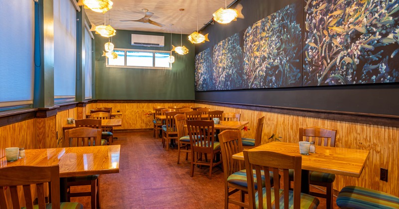 Interior, dining area, wooden tables and chairs, colorful fish mural on the wall