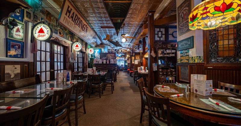 Interior of a restaurant with wooden tables and chairs in rows, vintage signage, and decorative stained glass lamps