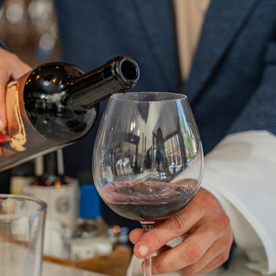 Hands pouring wine into a glass.
