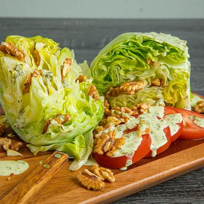 Wedge salad with iceberg lettuce, walnut, tomato and creamy dressing.