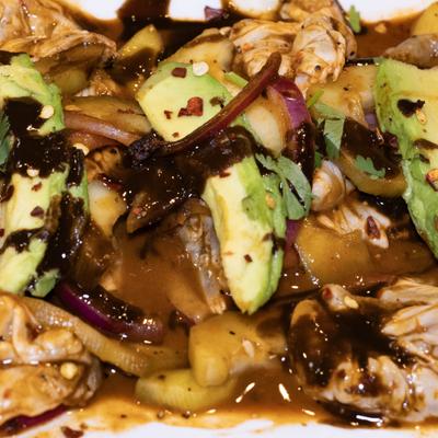 Raw seafood marinated in red salsa, with avocado, onion, and cilantro.