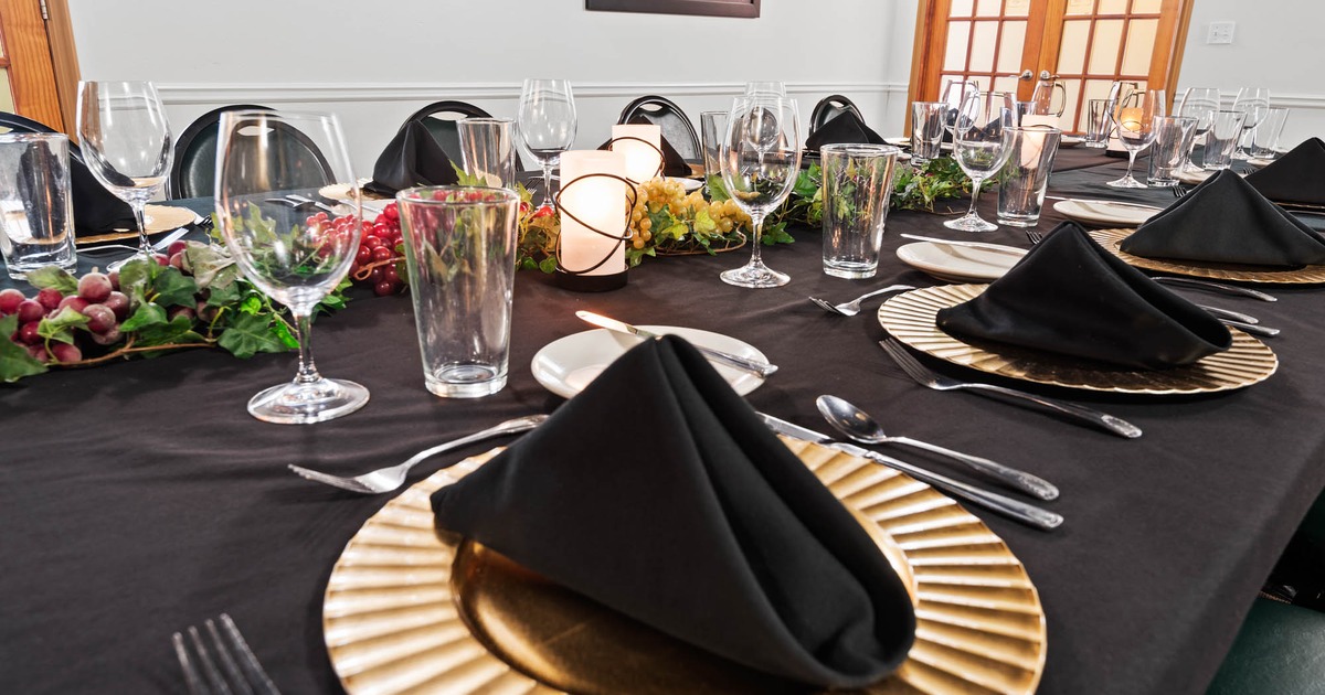 Close up of a banquet table with place setting, glasses, and faux greenery garnish