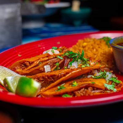 Quesabirria tacos with birria sauce and rice.