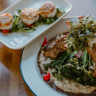 Lamb risotto served alongside plate of seared scallops.
