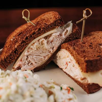 Toasted turkey and cheese sandwich on rye bread, served with coleslaw.