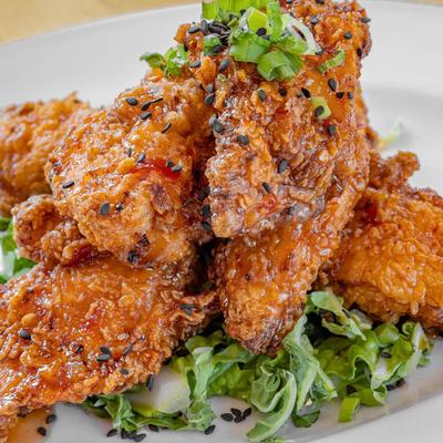 Crispy chicken wings with topped with sesame seeds and scallions, served over greens.