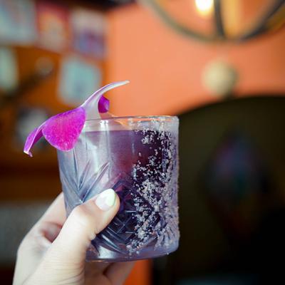 Purple cocktail drink, garnished with a purple flower