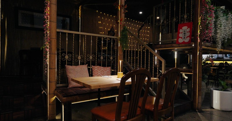 Rustic, bamboo-themed interior with a wooden table, cushioned seating and decorative lighting