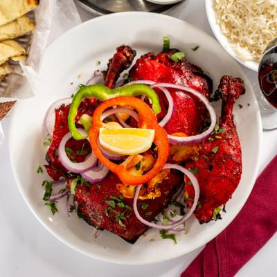 Bone in tandoori chicken topped with sliced red onion and bell peppers.