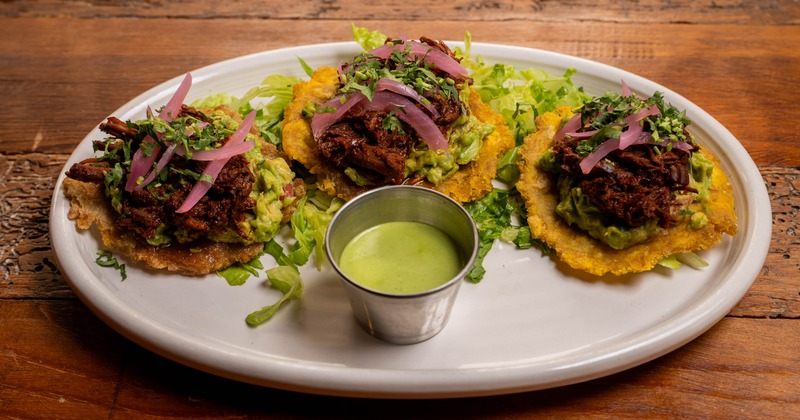 Tostadas topped with guacamole, chipotle chicken and pickled onions, served with a dip