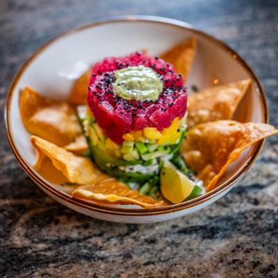 Ahi Tuna Tower served in a bowl with tortilla chips, placed on a textured surface.