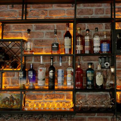 Bar shelving featuring metal frames, variety of bottles and a rustic brick background.