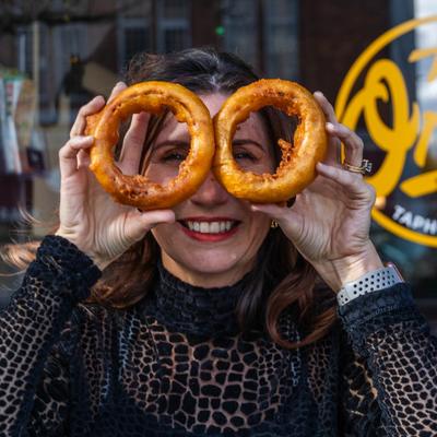 A person holding two large onion rings in front of their face.