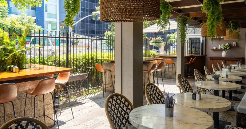 Outdoor seating area with marble tables, patterned chairs, pendant lights and hanging plants