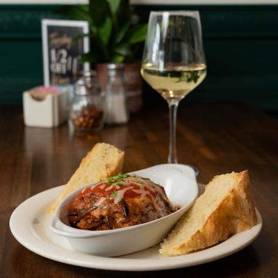 Eggplant Parmesan served served alongside bread and white wine.